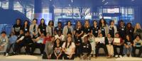 Group of CRNA residents with students from local school standing in front of blue wall